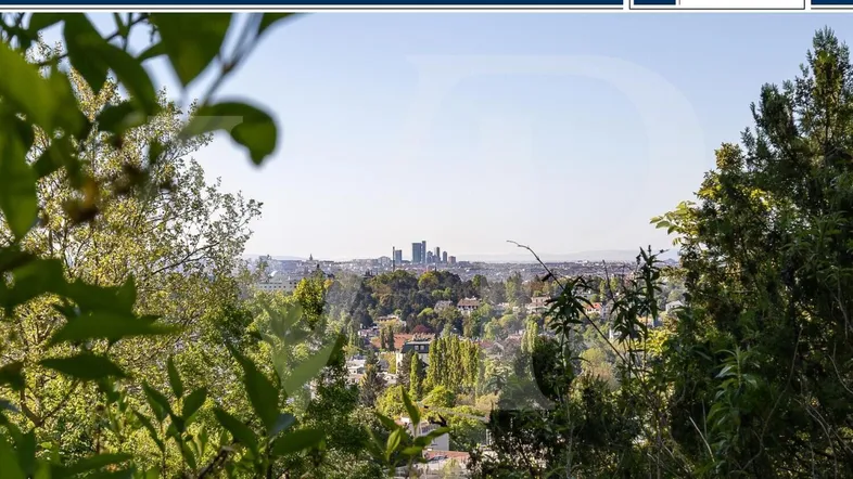 Panoramablick auf die Stadt mit Hochhäusern, umgeben von üppigem Grün und Bäumen.