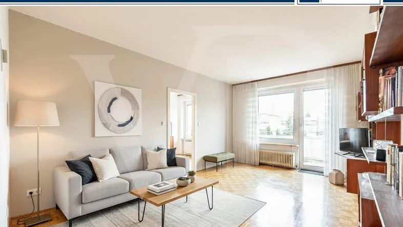 Helles Wohnzimmer mit Parkettboden, beiger Wandfarbe und Zugang zum Balkon.