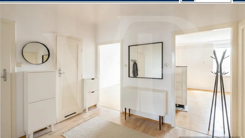 Heller Flur mit Parkettboden, Spiegel, Garderobe und weißem Schuhschrank.