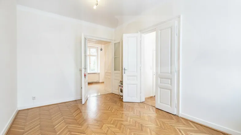 Helles Zimmer mit Fischgrätparkett und hohen weißen Türen, das vielseitig nutzbar ist.