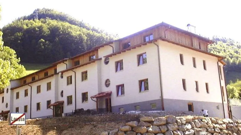 Neues Gebäude in massiver Bauweise mit Holzelementen und Blick auf die umliegende Berglandschaft.