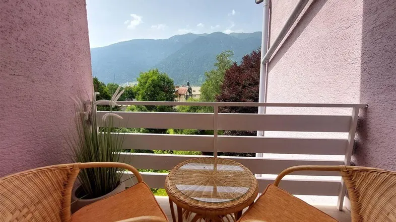 Gemütlicher Balkon mit Korbmöbeln und weitem Blick auf die umliegenden Berge.