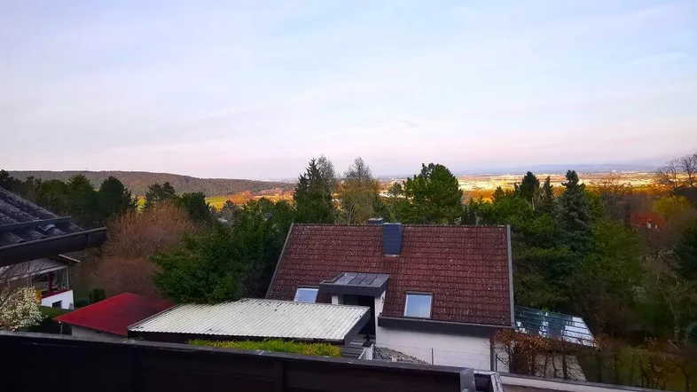 Geräumige Terrasse mit Ziegelboden und weitem Blick über die Landschaft und die Stadt in der Ferne.