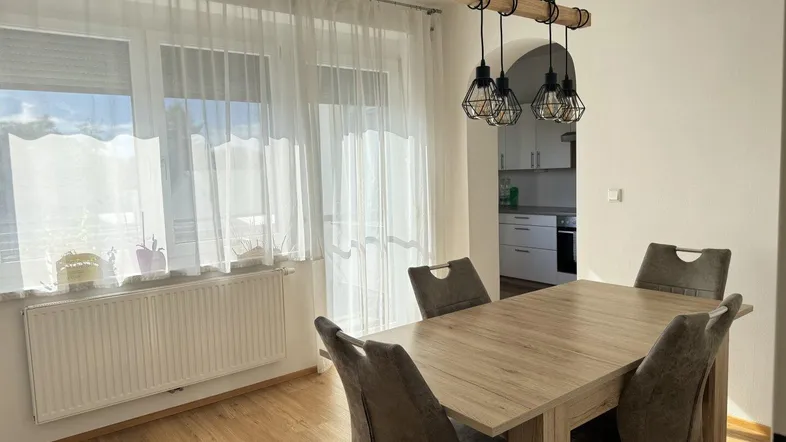 Heller Essbereich mit modernem Holztisch, bequemen Stühlen und Blick in die angrenzende Küche.