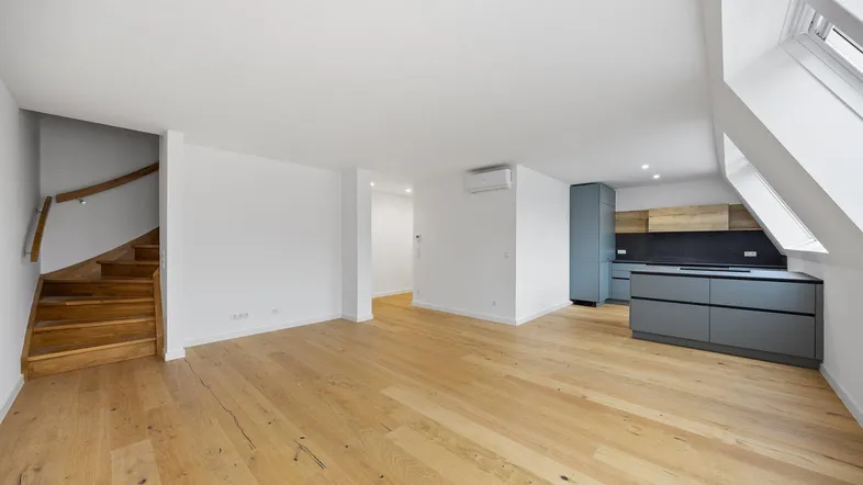 Heller offener Wohnbereich mit moderner Küche, Holztreppe und Dachfenstern, ideal für modernes Wohnen.