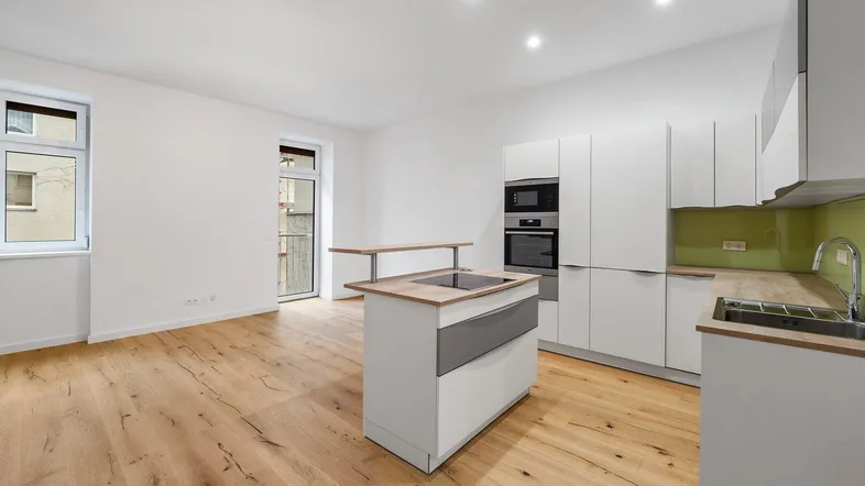 Moderne offene Küche mit Holzboden, weißen Schränken, Kücheninsel und Zugang zu einem kleinen Balkon.