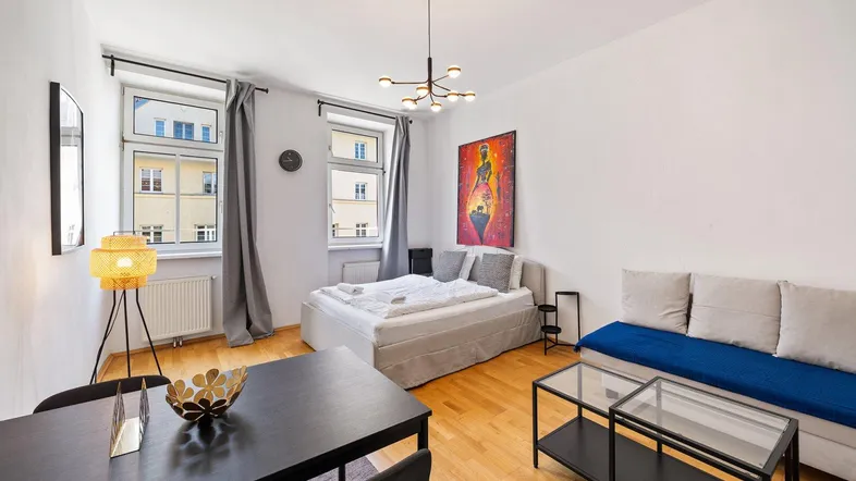 Helles und modern eingerichtetes Wohn-Esszimmer mit Schlafbereich und Holzboden.