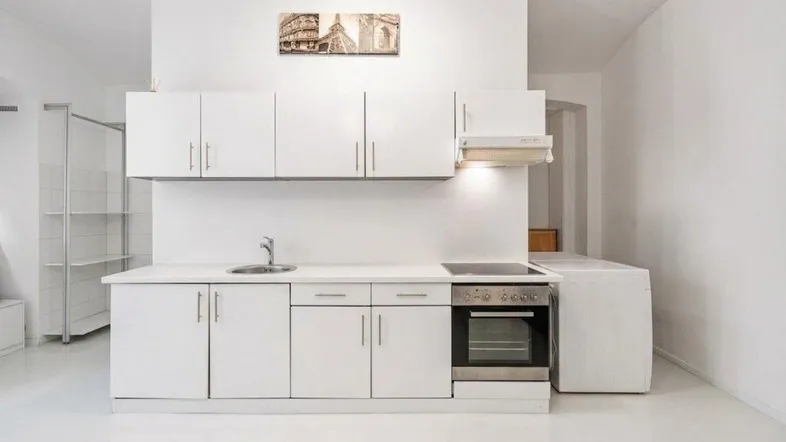 Moderne, helle Küchenzeile mit weißen Schränken, integriertem Backofen und Waschmaschine.