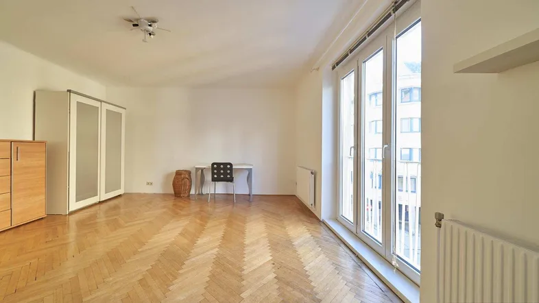 Helles Wohnzimmer mit Fischgrätparkettboden, großen Fenstern und viel Tageslicht.