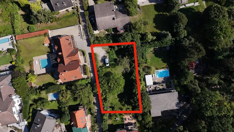 Luftaufnahme eines Wohngebiets mit einem rot umrandeten Grundstück und umliegenden Häusern mit Pools.