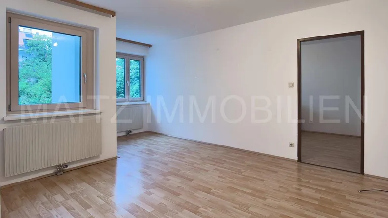 Helles Zimmer mit Parkettboden und zwei Fenstern, ideal als Wohn- oder Schlafzimmer nutzbar.