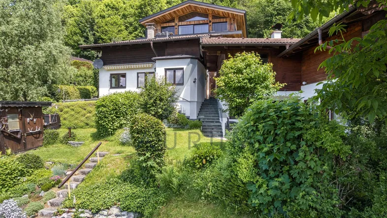 Charmantes Haus mit traditioneller Holzfassade und gepflegtem Garten in Hanglage.