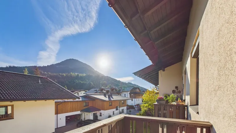 Sonniger Balkon mit Holzboden und atemberaubendem Blick auf die umliegende Berglandschaft.
