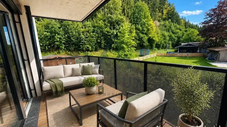Geräumiger Balkon mit modernen Outdoor-Möbeln und Blick ins Grüne, ideal zum Entspannen.
