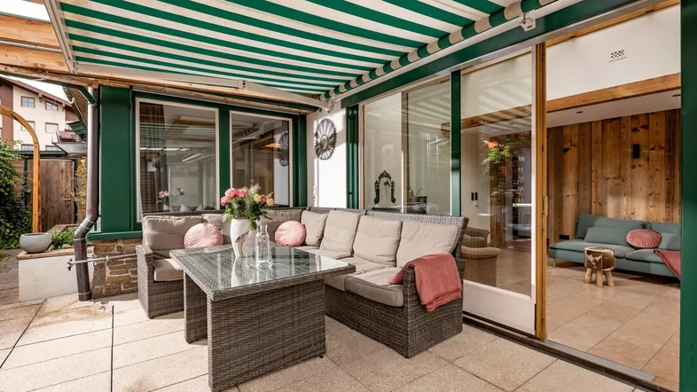 Gemütliche Terrasse mit bequemen Loungemöbeln und einer gestreiften Markise für angenehmen Schatten.
