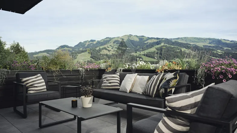 Moderne Terrasse mit bequemen Sitzmöbeln und weitem Blick auf die umliegende Berglandschaft.