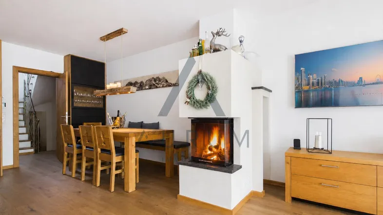 Heller Wohn- und Essbereich mit Holzboden, modernem Kamin und Zugang zum Treppenhaus.