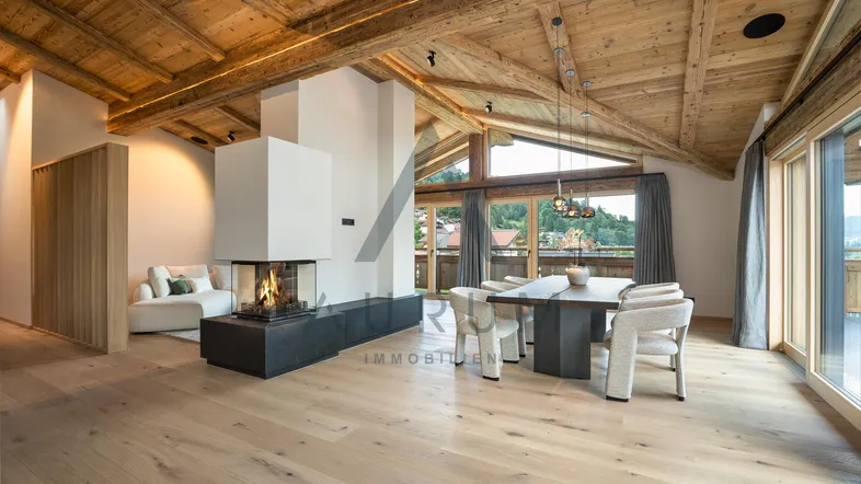 Geräumiger Wohn-Essbereich mit Holzbalkendecke, modernem Kamin und hellem Parkettboden.
