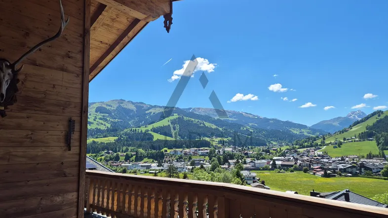 Geräumiger Holzbalkon mit traditioneller Dekoration und weitem Blick auf das Tal und die umliegenden Berge.