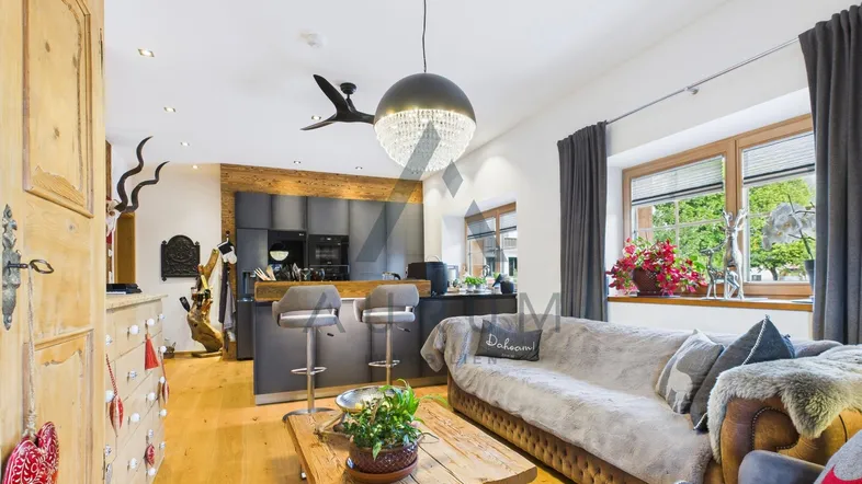 Geräumiger offener Wohnbereich mit moderner Küche, gemütlichem Sofa und traditionellen Holzelementen.