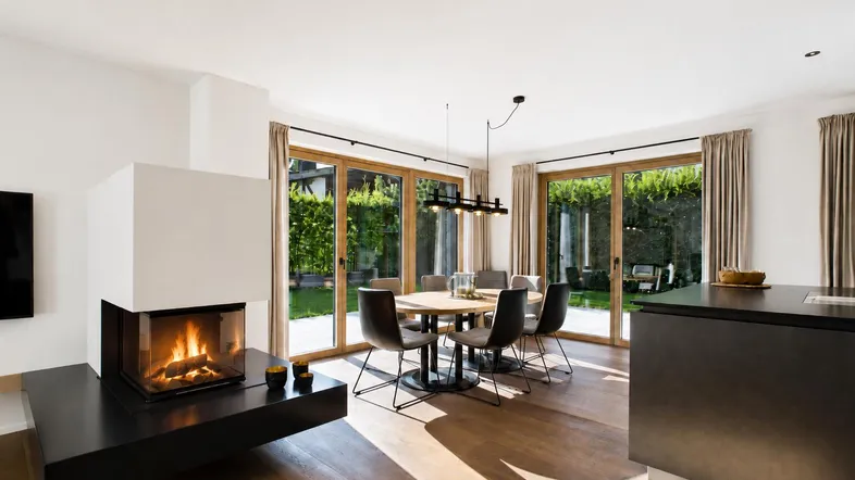 Heller Wohn- und Essbereich mit modernem Kamin, Holzboden und direktem Zugang zum Garten.