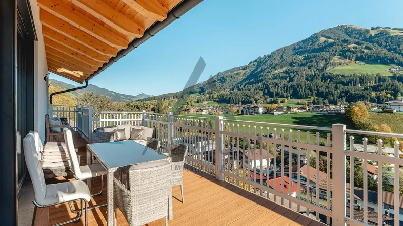 Geräumiger Balkon mit Sitzgelegenheiten und weitem Blick über die grüne Berglandschaft.