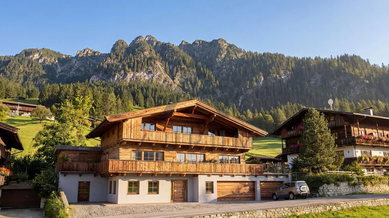 Traditionelles Holzhaus im alpinen Stil mit Balkonen und Bergblick auf die umliegende Landschaft.