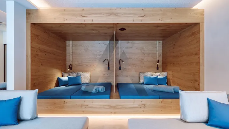 Gemütliche Holzkojen mit blauen Matratzen in einem Entspannungsbereich, ideal für Wellness.