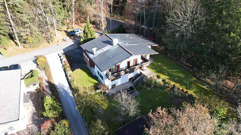 Luftaufnahme eines Hauses mit Solaranlage auf dem Dach und großem Grundstück.