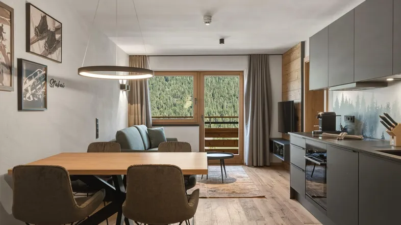 Moderner Wohn-Essbereich mit offener Küche, Holzboden und Bergblick vom Balkon.