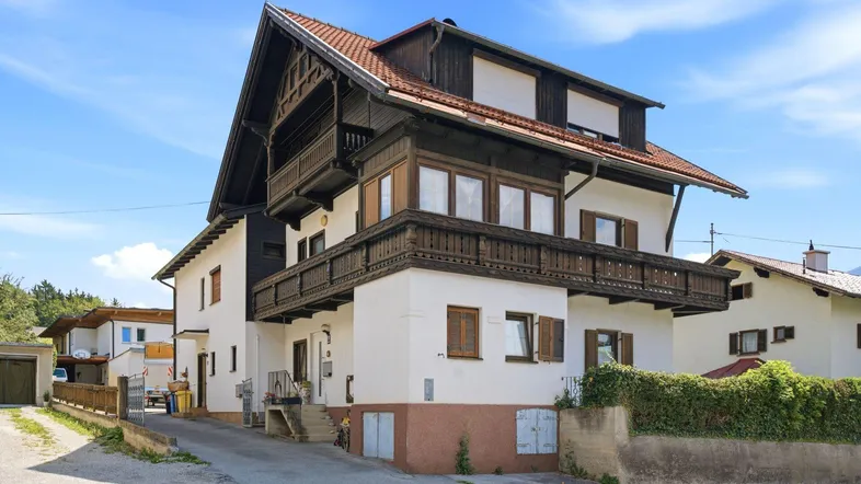 Traditionelles Haus mit Holzbalkonen und Satteldach in ländlicher Umgebung.