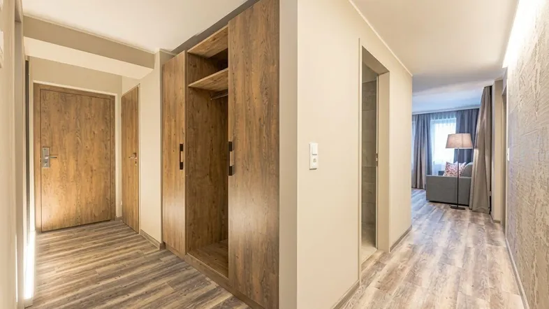 Moderner Flur mit integriertem Holzschrank und hellem Laminatboden, der zu den Wohnbereichen führt.