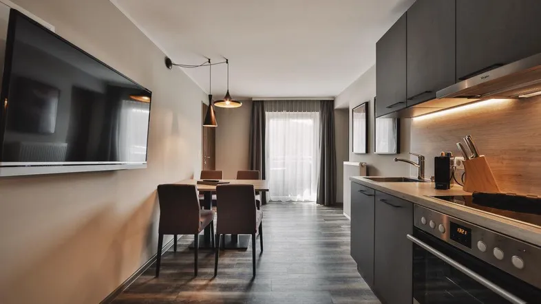 Moderner offener Wohn-Essbereich mit integrierter Küche, Laminatboden und Zugang zum Balkon.