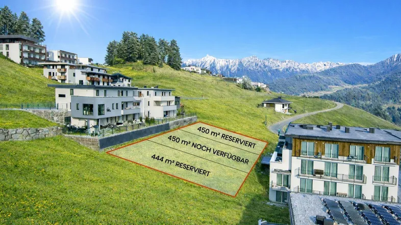 Luftaufnahme eines Baugrundstücks in Hanglage mit umliegenden modernen Gebäuden und Bergblick.
