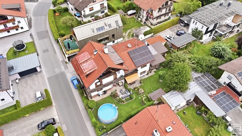 Luftaufnahme eines Wohnhauses mit Garten, Pool und Photovoltaikanlage in einer ländlichen Umgebung.
