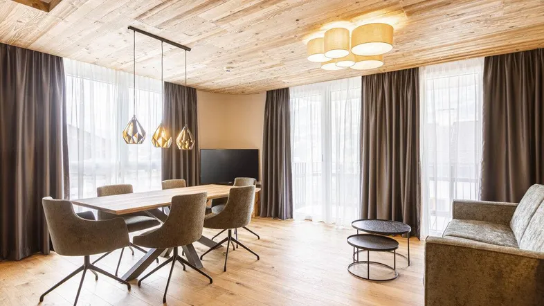 Geräumiger Wohn-Essbereich mit Holzbalkendecke, modernem Esstisch und gemütlichem Sofa.