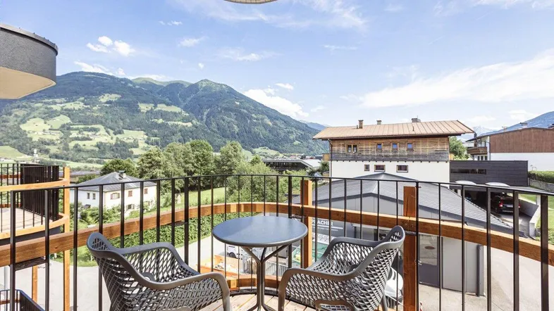 Möblierter Balkon mit Holzboden und weitem Blick auf die umliegende Berglandschaft.