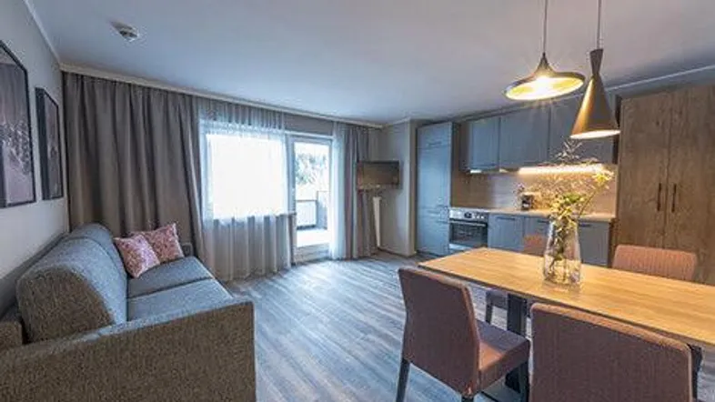 Moderner offener Wohn- und Essbereich mit integrierter Küchenzeile und Zugang zum Balkon.