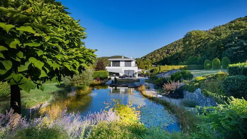 Moderne Villa mit großem Naturteich und üppiger Gartenanlage in sonniger Hanglage.