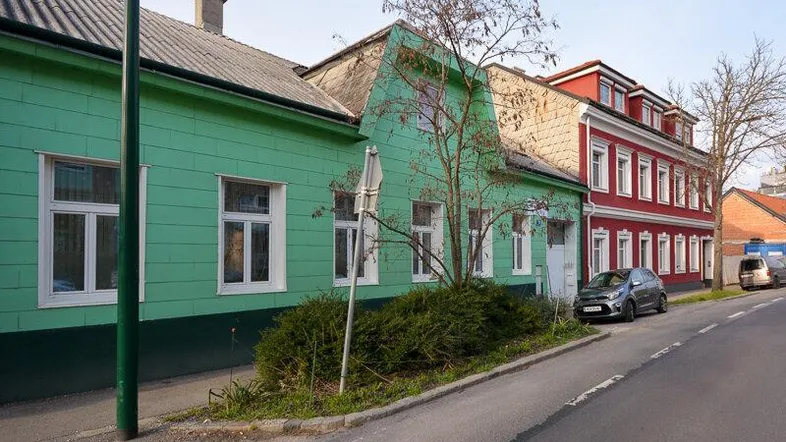 Bunte Fassaden von Wohnhäusern entlang einer ruhigen Straße mit parkenden Autos.