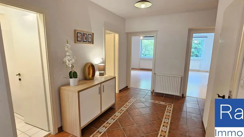 Heller Flur mit Terrakotta-Fliesenboden, Holzschrank und Zugang zu weiteren Räumen.