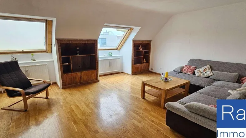 Helles Wohnzimmer mit Holzboden, gemütlicher Sitzecke und Dachschrägenfenstern.