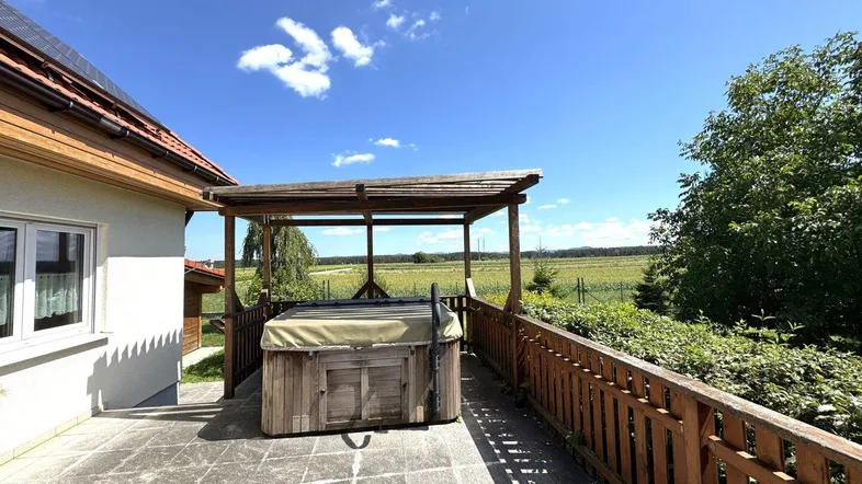 Große gepflasterte Terrasse mit Whirlpool und weitem Blick über die umliegende Landschaft.