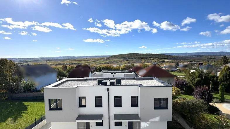 Moderne Reihenhäuser mit Flachdach und weitem Blick über die grüne Landschaft.