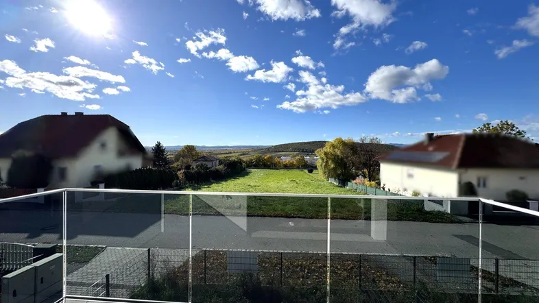Sonniger Balkon mit Glasgeländer und weitem Blick über die Landschaft.