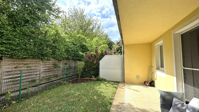 Gepflegter Gartenbereich mit Rasenfläche und Sichtschutz durch hohe Hecken und Bäume.