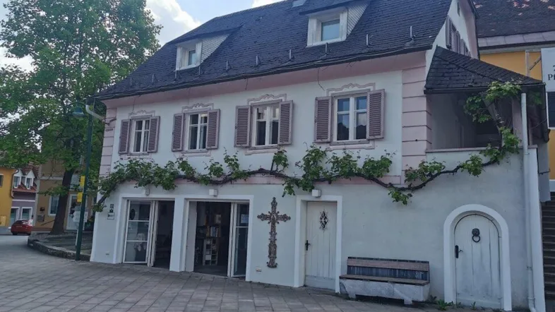 Historisches Gebäude mit traditioneller Fassade, Fensterläden und begrüntem Eingangsbereich.
