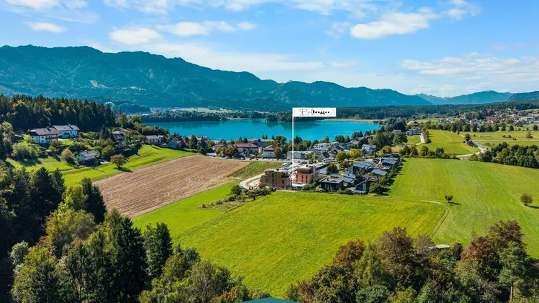 Panoramablick aus der Vogelperspektive auf die Liegenschaft mit See- und Bergblick in grüner Umgebung.