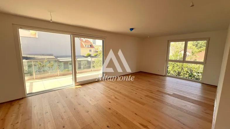 Helles Wohnzimmer mit Holzboden und großen Schiebetüren, die auf eine Terrasse führen.