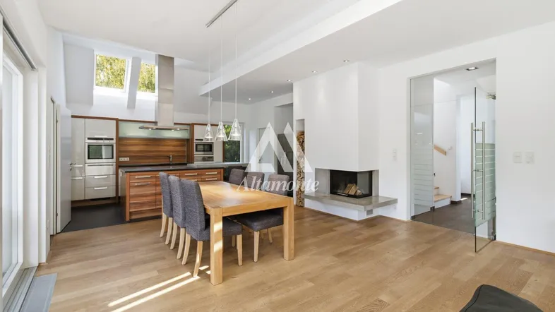 Heller, offener Wohn- und Essbereich mit moderner Küche, Kamin und Zugang zum Garten.